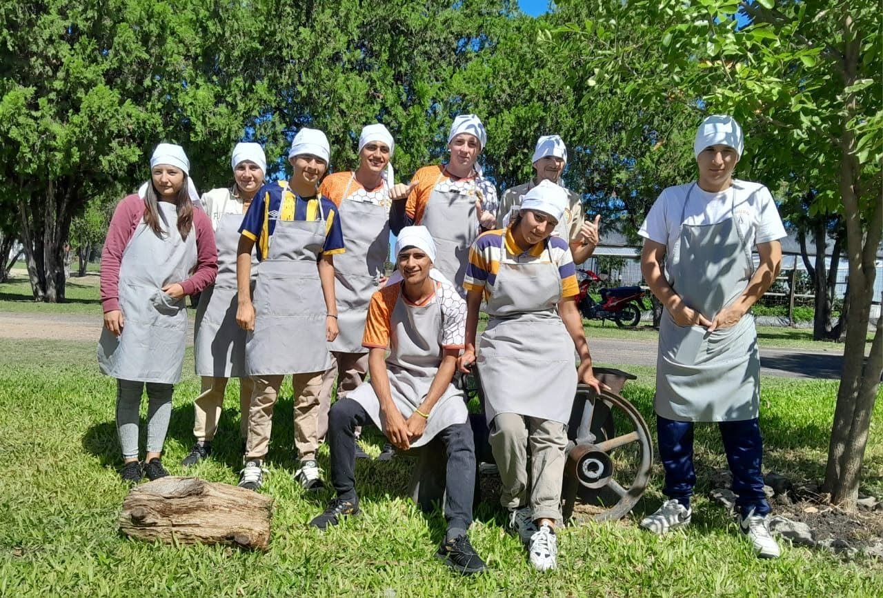 Estudiantes con delantal y cofia listos para trabajar en la planta de elaboración